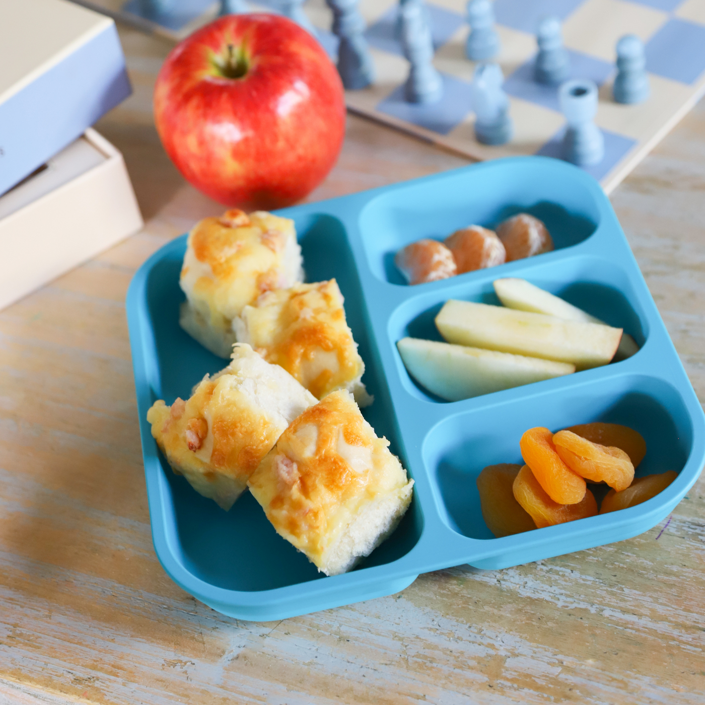 bobo&boo plant-based divided bento plate in blue with cheese scrolls, apple & mandarins in them 