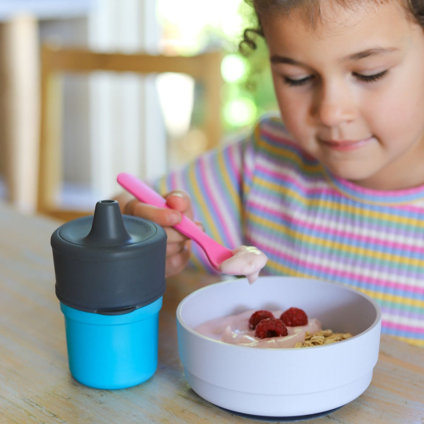 girl using a pink bobo&boo plant-based fork to eat her yoghurt & muesli