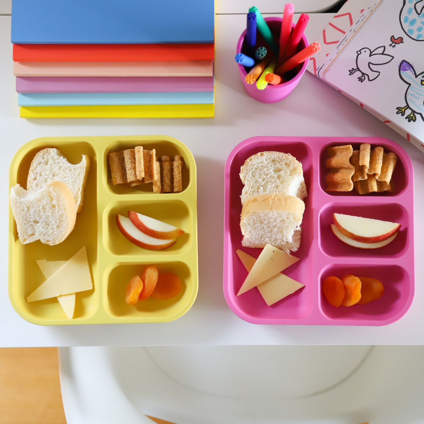 bamboo plant-based divided plates with snacks in them sitting on a desk