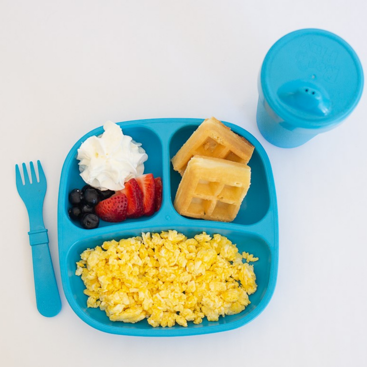Children's lunch with waffles, fruit, and rice on a blue tray with a fork and cup. RePlay Recycled Divided Plate - Sky Blue