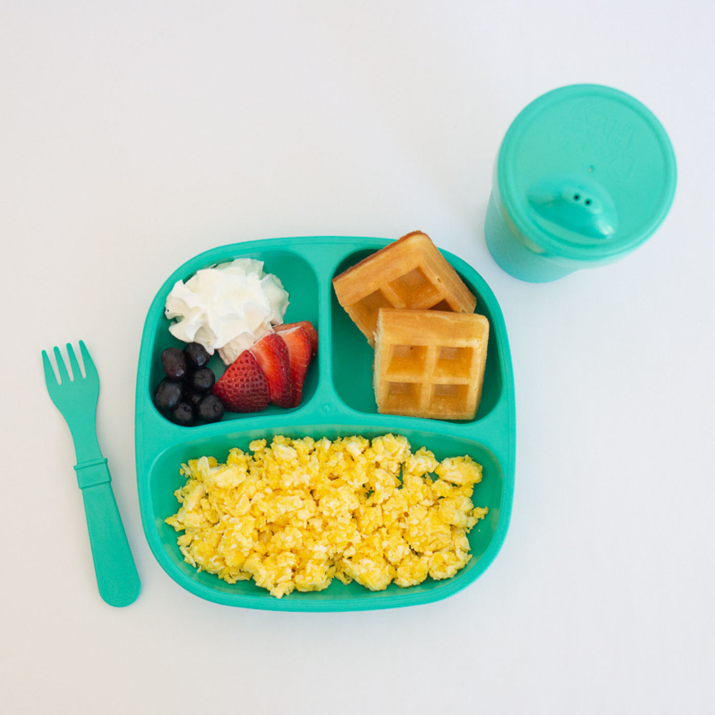 Children's lunch with waffles, fruit, and rice on a green tray with a green cup and fork. RePlay Recycled Divided Plate - Teal