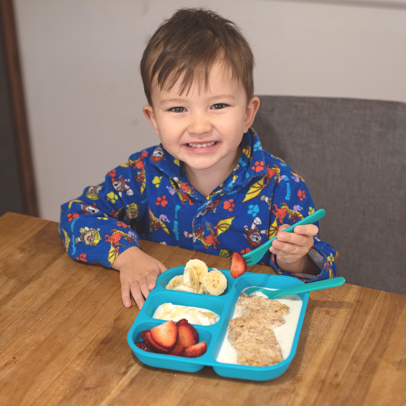 a boy happily eating his weetbix breakfast with his bobo&boo plant-based divided plate & fork & spoon