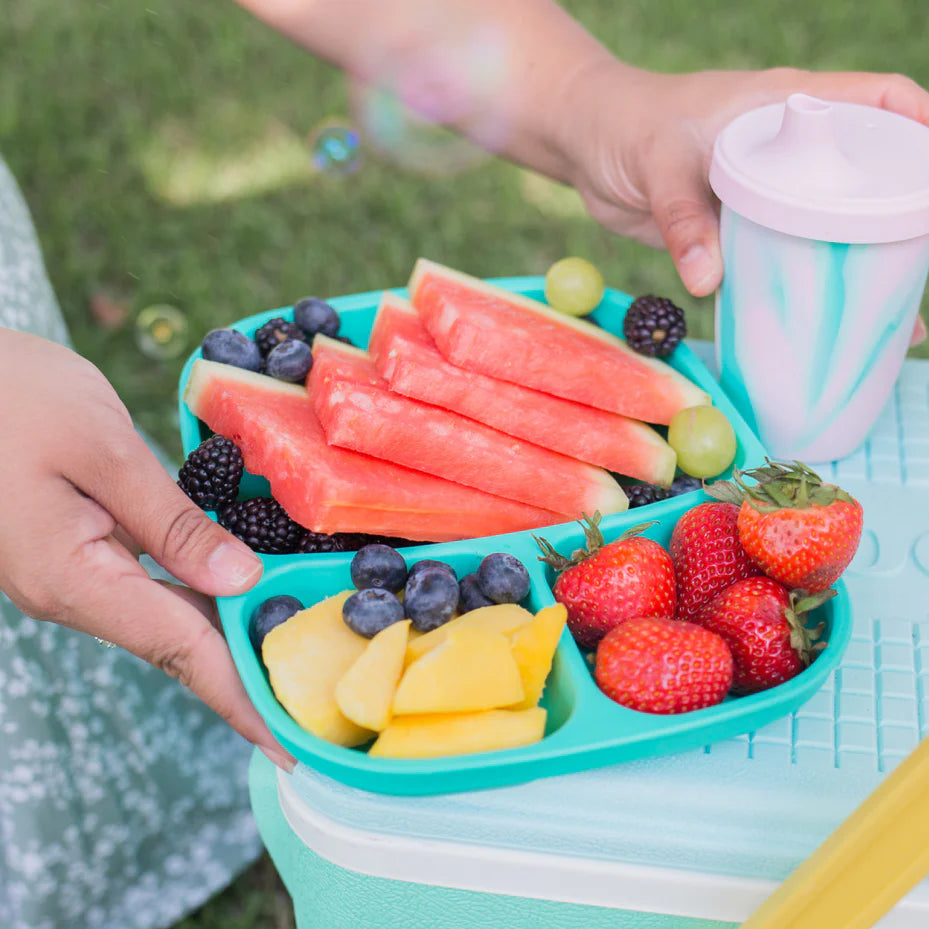 Children's hands holding a colorful fruit tray with watermelon, berries, and grapes, next to a white cup. RePlay Recycled Divided Tray Plate - Aqua
