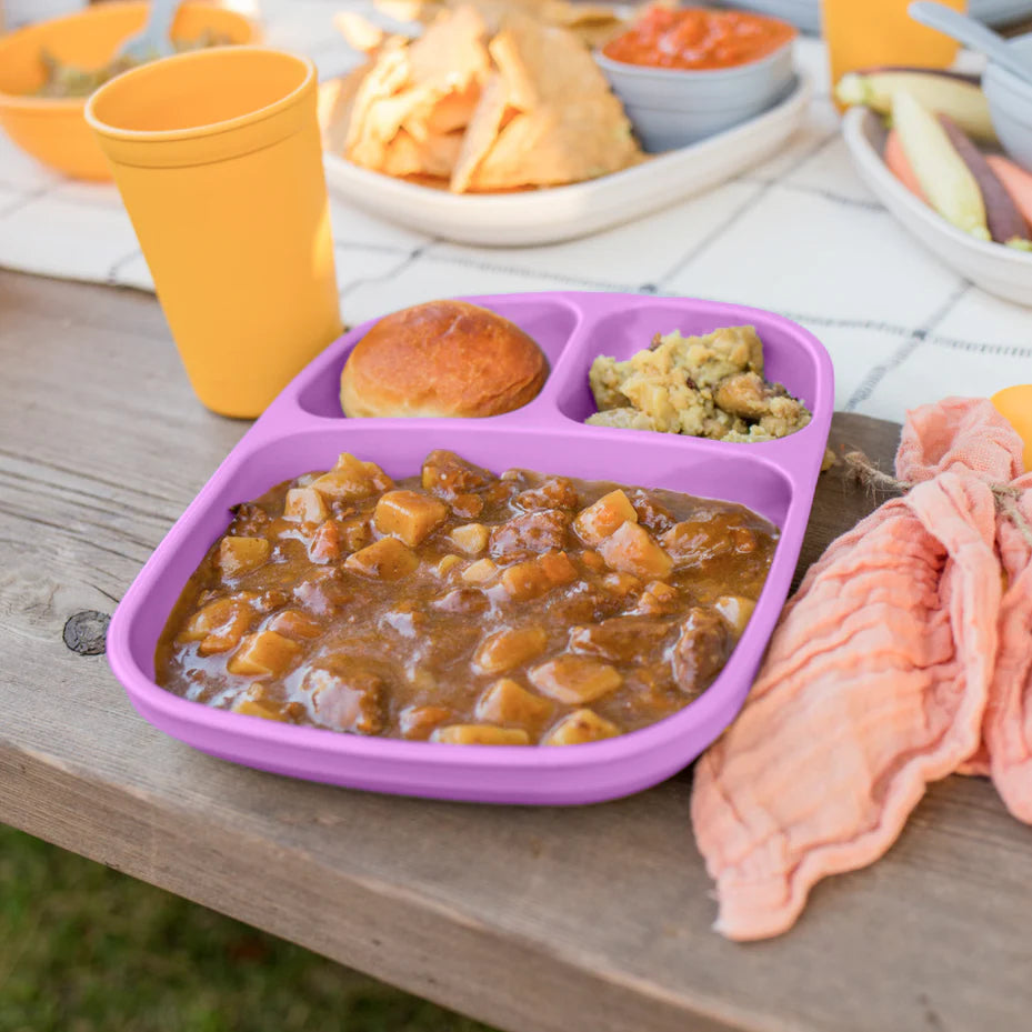 Purple divided plate with food on a wooden table outdoors. RePlay Recycled Divided Tray Plate - Purple
